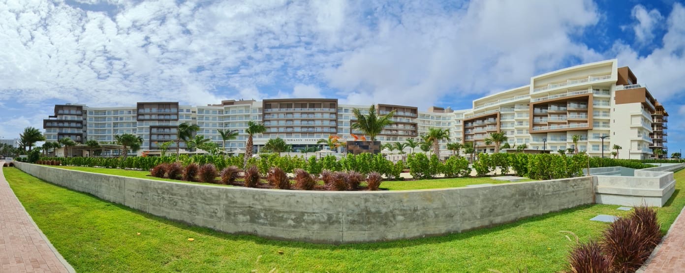 Panoramic view of the Embassy Suites hotel behind a concrete retaining wall and lawn