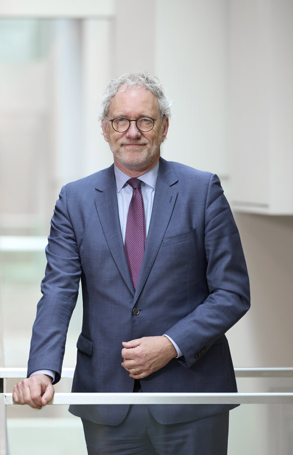 Portrait of a man in a blue suit and tie standing beside a railing