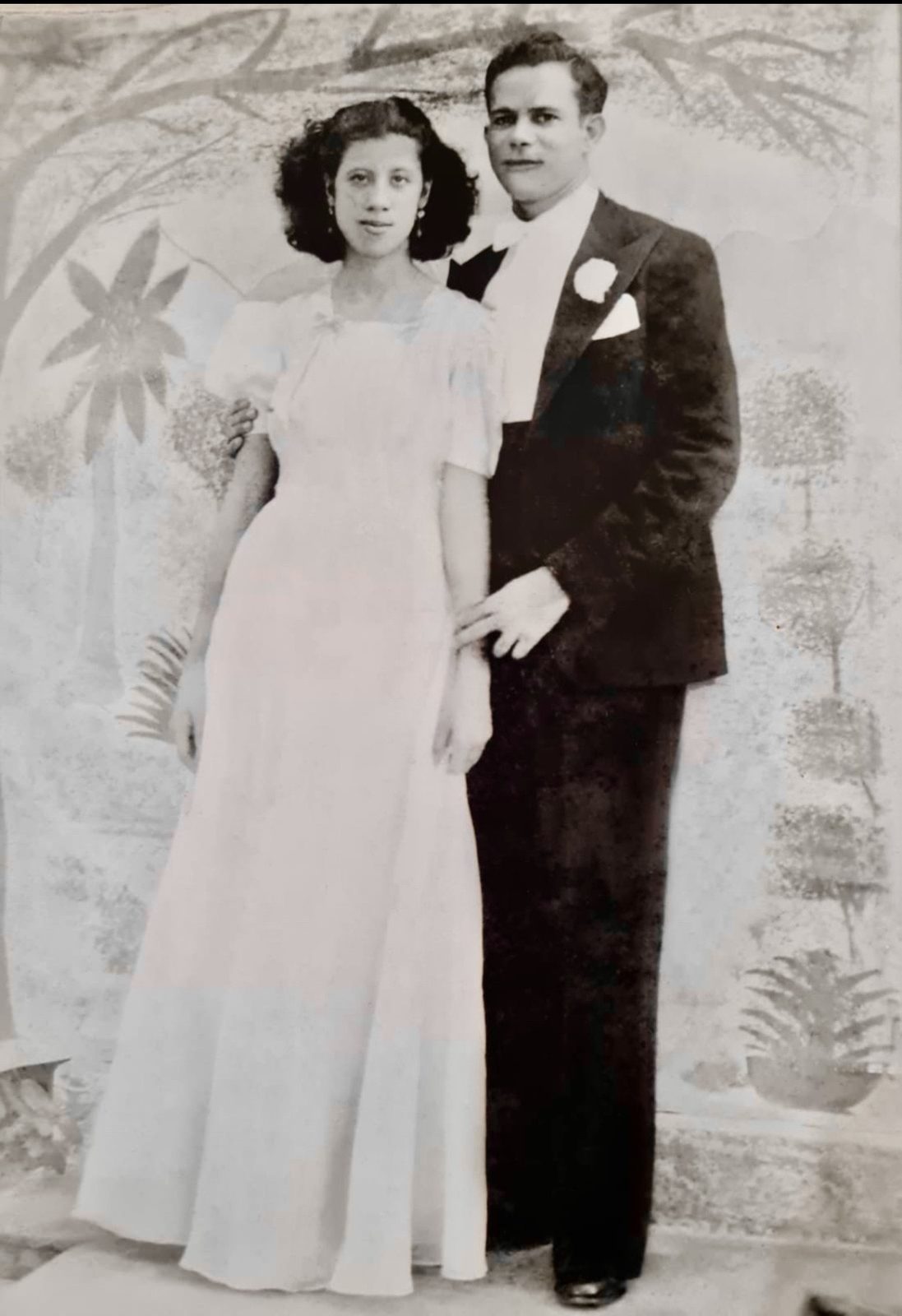 Archival studio wedding portrait of a couple in evening dress before a painted backdrop